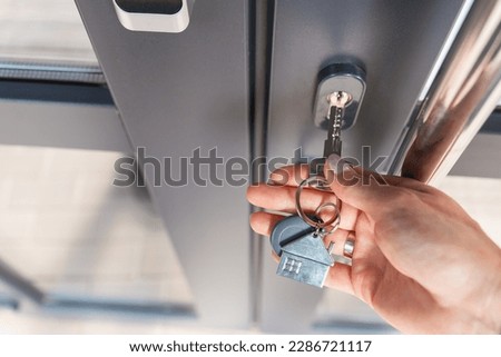 A woman's hand opens the door with a key on which the keychain hangs at home. Selective focus, noise.