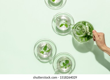 Woman's Hand Pouring Fresh Leaf Mint Tea In A Glass Cup, View From Above, Blank Space For A Text