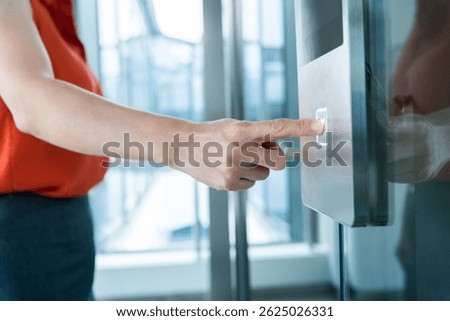 Woman's hand presses the elevator button