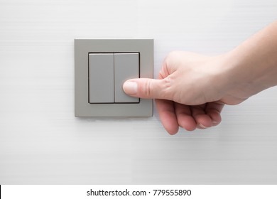 Woman's hand pressing light switch at the wall.