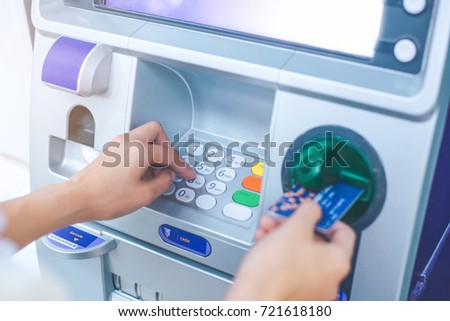 Woman's hand pressing PIN/pass code on ATM/bank machine keypad,And inserting debit card
