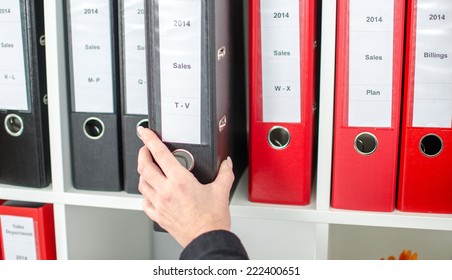 Woman's hand pulling out a folder from a shelf