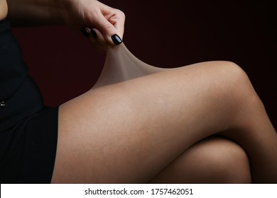 woman's hand pulling tights on her leg