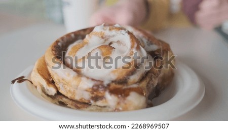 Woman's hand pushes the cinnabon cake further away. Concept tease, take away, punish.