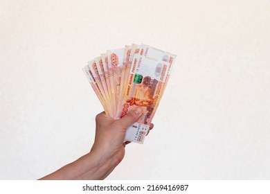 A Woman's Hand, Raised Up, Holds Russian Money Worth Five Thousand Rubles On A Light Background