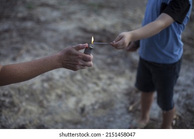 Woman's Hand Reaches Out With A Lighter To Light A Child's Sparkler Stick 