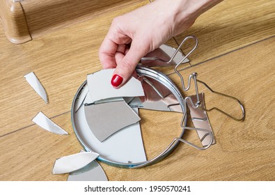 Woman's Hand Removes Broken Pieces Of Mirror From Wooden Floor At Home