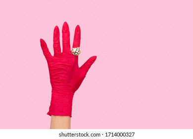 Womans Hand In A Rubber Glove With Golden Ring On Pink Background. Stay Safe Mock Up Template With Copy Space