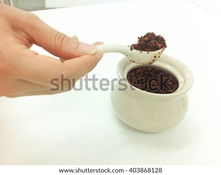 Woman's hand scooping cayenne pepper from flavouring cup.
