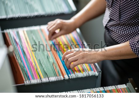 Woman's hand searching for documents at the filing cabinet