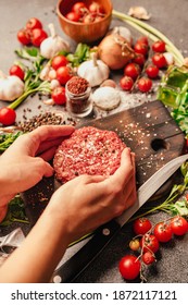 Woman's hand seasoning and forming a beef meat patty for a hamburger barbecue. Portioning butcher's ground meat.Homemade burger recipe.Spices and condiments for a grill. Making delicious food at home.