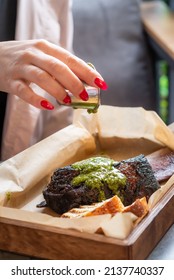 Woman's Hand Seasoning A Smoked Beef Back Rib With Green Sauce