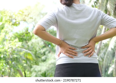 Woman's hand She is caught at the waist and her back is painful at the back in the park. Cause of the exercise. - Shutterstock ID 2190787271