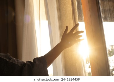 woman's hand She opened the curtains on the window. There was morning light through the window in her room, looking at the view of the mountains and trees as the sun rose. - Powered by Shutterstock