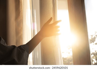 woman's hand She opened the curtains on the window. There was morning light through the window in her room, looking at the view of the mountains and trees as the sun rose. - Powered by Shutterstock