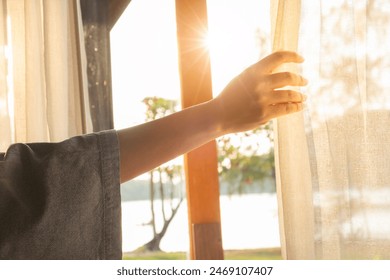 woman's hand She opened the curtains on the window. There was morning light through the window in her room, looking at the view of the mountains and trees as the sun rose. - Powered by Shutterstock