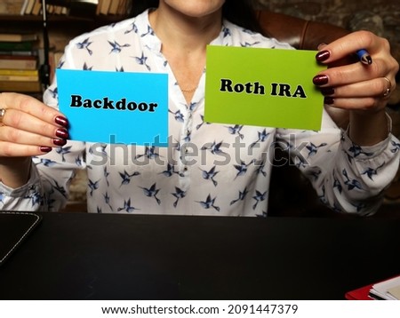 Woman's hand showing green and blue business cards with phrase Backdoor Roth IRA - closeup shot on grey background
