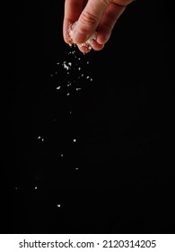 A woman's hand sprinkles salt on a black background. Levitation. Minimalism. Seasonings, spices. Ingredient for various dishes. Restaurant, hotel, cafe, supermarket. Advertising. - Shutterstock ID 2120314205