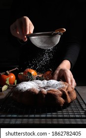 Woman's hand sprinkling icing sugar over fresh bundt cake. Dark background. - Shutterstock ID 1862782405