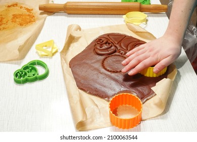 A woman's hand squeezes cookies out of the rolled dough with a cutter.                               