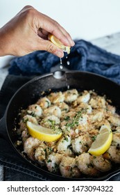 Woman's Hand Squeezing Fresh Lemon Juice On Shrimp Scampi