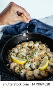 Woman's Hand Squeezing Fresh Lemon Juice On Shrimp Scampi