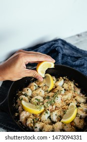 Woman's Hand Squeezing Fresh Lemon Juice On Shrimp Scampi