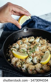 Woman's Hand Squeezing Fresh Lemon Juice On Shrimp Scampi