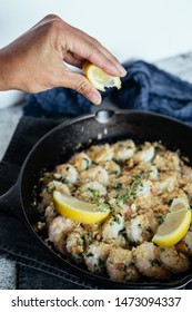 Woman's Hand Squeezing Fresh Lemon Juice On Shrimp Scampi