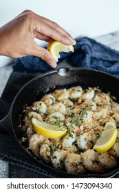 Woman's Hand Squeezing Fresh Lemon Juice On Shrimp Scampi