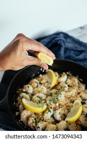 Woman's Hand Squeezing Fresh Lemon Juice On Shrimp Scampi