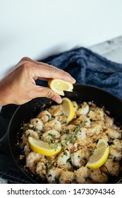 Woman's Hand Squeezing Fresh Lemon Juice On Shrimp Scampi