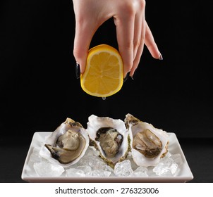 Woman's Hand Squirt Three Oyster Shell With Lemon Juice, Dark Background