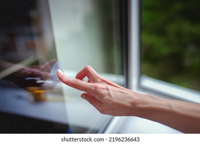 
A woman's hand sticks decals on windows for birds. These decals has a special coating that reflects ultraviolet sunlight, which help prevent wild birds from accidentally striking windows. - Shutterstock ID 2196236643