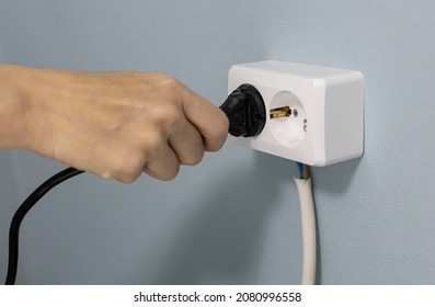 A Woman's Hand Sticks A Power Cord Into An Electrical Outlet. High Quality Photo