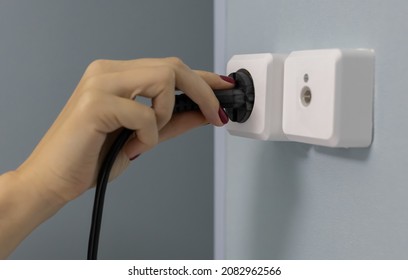 A Woman's Hand Sticks A Power Cord Into An Electrical Outlet (corrected)