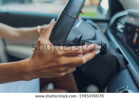 Woman's hand switches the lobes of the gear selector on the steering wheel. Hand is switching car gear lever, close up shot of a manual gear changing paddle on a car's steering wheel.