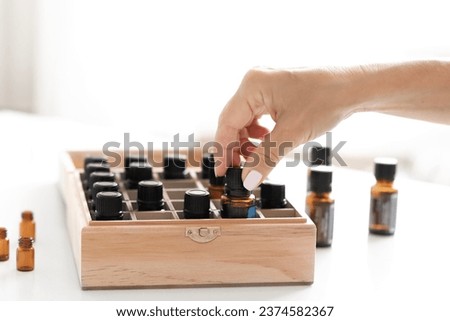 Woman's hand takes out a bottle of essential oil from a wooden box.  essential oils in wooden box. Herbal alternative medicine with essential oils bottles in wooden box, healthy organic natural therap