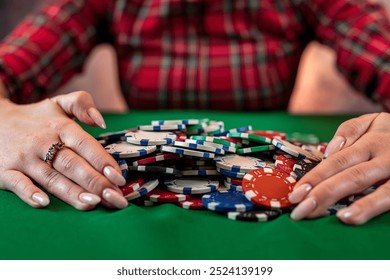 woman's hand takes poker chips from a pile at a round poker table. risky bets in poker. a woman plays a man's game - Powered by Shutterstock