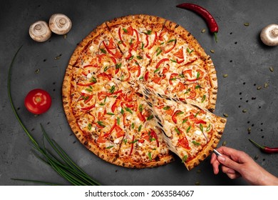 A woman's hand takes a slice of pizza with a spatula and the cheese stretches, top view.