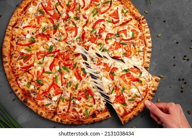 A woman's hand takes a slice of pizza with a spatula and the cheese stretches, top view, close-up. - Powered by Shutterstock