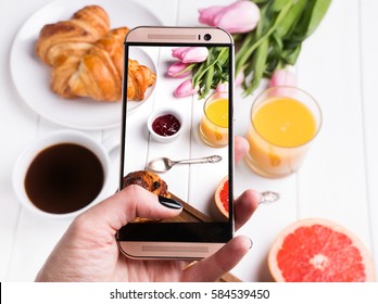 Woman's hand taking photo of delicious breakfast with smart phone close-up - Powered by Shutterstock