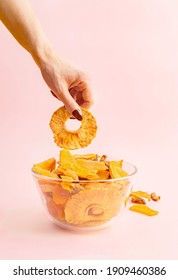 Woman's Hand Taking Pineapple Ring From A Bowl With Fruit Jerky