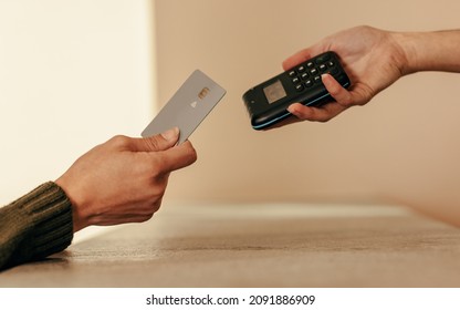 Woman's Hand Tapping A Credit Card On A Contactless Card Reader. Unrecognizable Female Customer Paying With A Credit Card At The Checkout Counter.