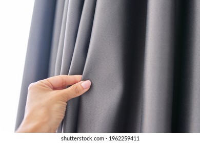 Woman's hand touching curtain  gray blackout fabric  light  blocking fabric