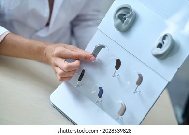 Womans hand touching hearing aid at stand - Shutterstock ID 2028539828