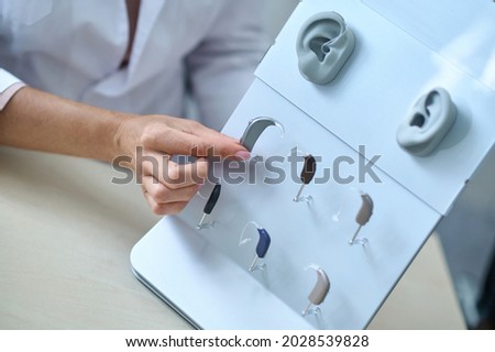 Womans hand touching hearing aid at stand