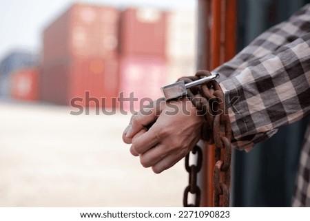  woman's hand trapped in an illegally smuggled container locked with chain and key. Efforts to escape from the confinement were tortured : Human Trafficking and Illegal Immigration.