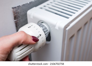 Woman's Hand Turning A Heating Thermostat. Heater Temperature Control To Save Natural Gas, Lower Utility Bills.