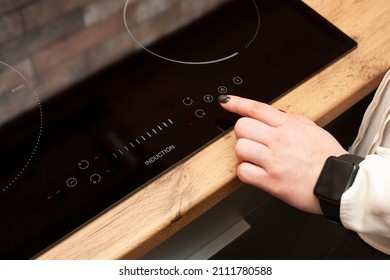 A woman's hand turns on an induction furnace. Cooking. Touch panel induction furnace.
